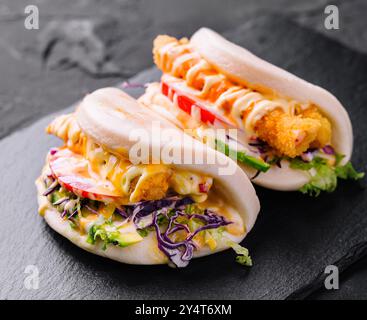 Délicieux petits pains au poulet bao servis sur une assiette en ardoise, parfaits pour les menus de la cuisine asiatique moderne Banque D'Images