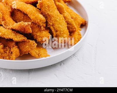 Filets de poulet dorés frits servis sur une assiette blanche avec ketchup, parfaits pour une collation ou un repas rapide Banque D'Images