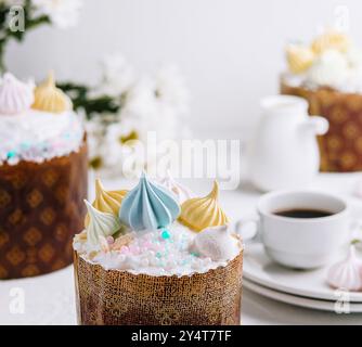 Kulich traditionnel de pâques garni de glaçage pastel et de merengues, servi avec du thé Banque D'Images