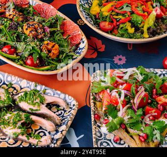 Cuisine méditerranéenne animée servie dans des bols décoratifs sur une nappe à motifs avec des ingrédients frais en toile de fond Banque D'Images