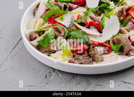 Carpaccio de boeuf en tranches orné de copeaux de parmesan, de roquette et de poivrons rouges Banque D'Images