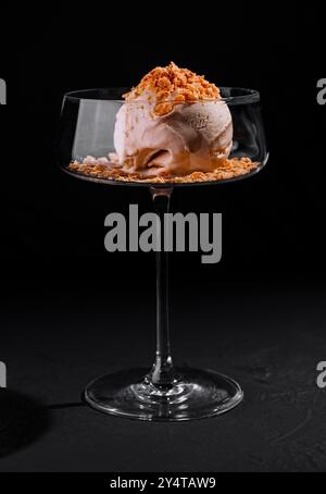 Dessert de crème glacée plaqué avec crumble garniture dans un verre coupé élégant sur un fond sombre Banque D'Images