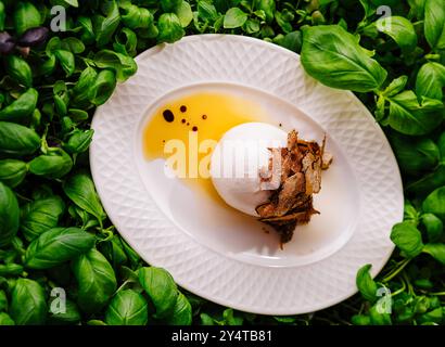 oeuf poché avec copeaux de truffe servis sur un lit de feuilles de basilic frais Banque D'Images