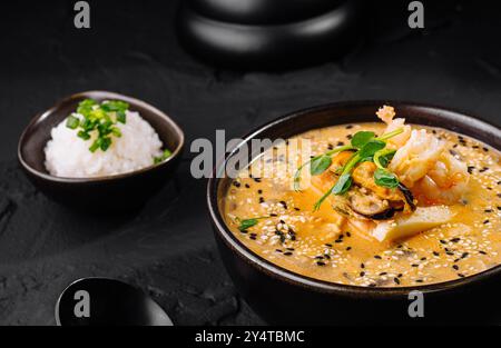 Ragoût de kimchi appétissant servi avec du riz sur un fond sombre et texturé Banque D'Images