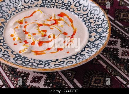 Houmous maison garni d'huile d'olive et de paprika sur une assiette décorative Banque D'Images