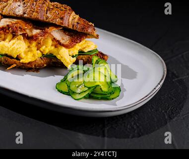 Délicieux sandwich gourmand au petit déjeuner avec œufs brouillés. Bacon. Et avocat sur un croissant fraîchement cuit. Parfait pour un salé et sain Banque D'Images