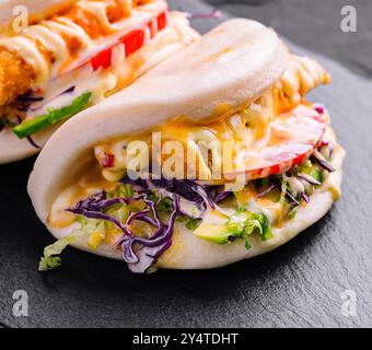 Délicieux petits pains au poulet bao servis sur une assiette en ardoise, parfaits pour les menus de la cuisine asiatique moderne Banque D'Images