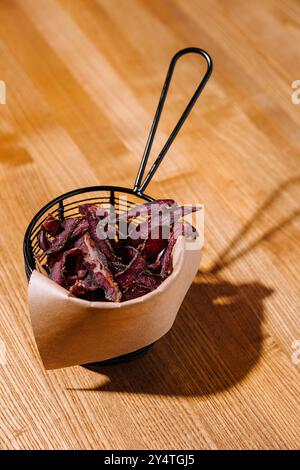 Cornet de frites de bœuf gourmandes servi dans un élégant panier en fil de fer, parfait pour une collation saine Banque D'Images