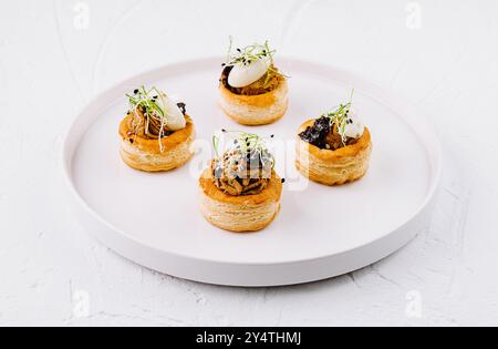 Elégante pâte feuilletée vol-au-vent avec garniture salée, servie sur une assiette blanche immaculée Banque D'Images