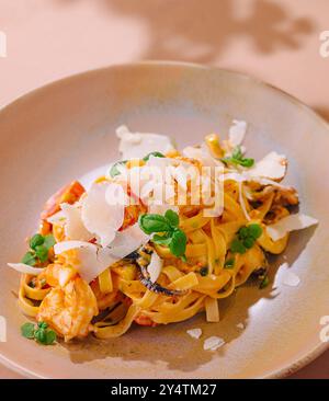 Service élégant de pâtes tagliatelles avec crevettes, champignons et copeaux de parmesan garni d'herbes fraîches Banque D'Images