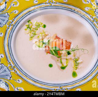 Soupe gourmande servie dans une assiette décorative avec placage artistique sur fond pêche Banque D'Images