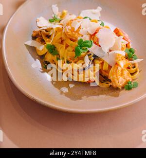 Service élégant de pâtes tagliatelles avec crevettes, champignons et copeaux de parmesan garni d'herbes fraîches Banque D'Images