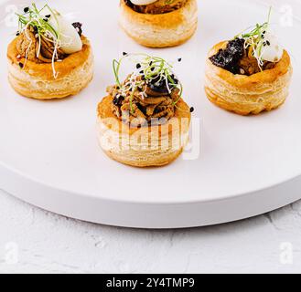 Elégante pâte feuilletée vol-au-vent avec garniture salée, servie sur une assiette blanche immaculée Banque D'Images