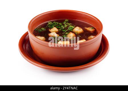 Soupe aux croûtons et aux herbes servies dans un bol brun debout sur une assiette Banque D'Images