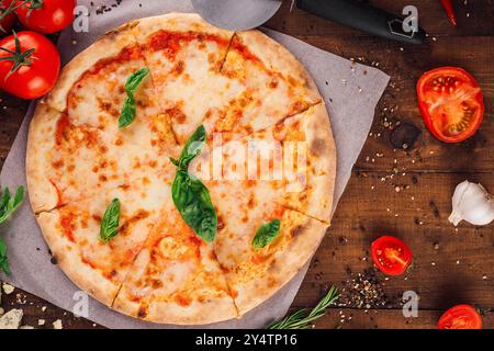 Pizza margherita fraîchement cuite avec fromage mozzarella et feuilles de basilic sur fond de bois rustique Banque D'Images