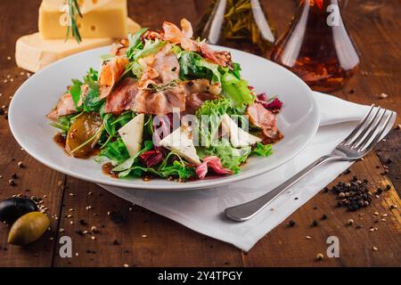 Salade fraîche au jambon, poire et fromage bleu dor assaisonné d'huile et sauce aux herbes servies sur assiette blanche Banque D'Images