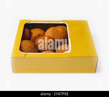 Boîte en carton jaune pleine de biscuits fraîchement cuits avec fenêtre en plastique transparent sur fond blanc Banque D'Images