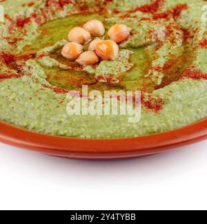 Houmous de pois verts garni de paprika et d'huile d'olive dans un bol en terre cuite Banque D'Images