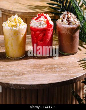 Trois milkshakes avec différentes saveurs et garnitures sont assis sur une table Banque D'Images