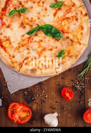 Pizza margherita fraîchement cuite avec fromage mozzarella et feuilles de basilic sur fond de bois rustique Banque D'Images