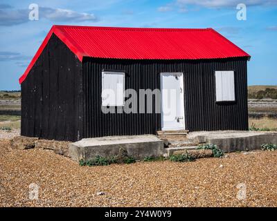 Une cabane noire au toit rouge, connue sous le nom de cabane des pêcheurs, est située à Rye Harbour, près de l'embouchure de la rivière Rother Banque D'Images