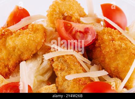 Gros plan d'une salade de poulet croustillante gourmande avec laitue fraîche. Poulet pané. Fromage râpé. Tomates cerises. Et d'autres légumes nutritifs Banque D'Images