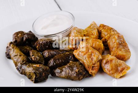 Assiette blanche avec des rouleaux de chou farcis de viande hachée et de riz assaisonnés d'herbes et d'épices servies avec de la crème sure Banque D'Images