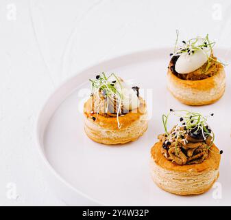 Elégante pâte feuilletée vol-au-vent avec garniture salée, servie sur une assiette blanche immaculée Banque D'Images