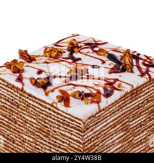 Gâteau au miel en couches recouvert de glaçage blanc, arrosé de caramel et saupoudré de noix sur fond blanc Banque D'Images