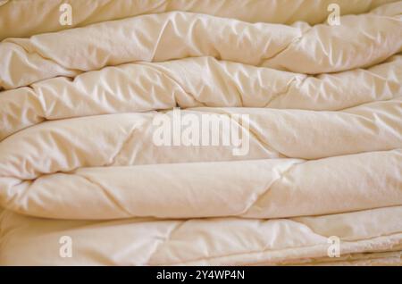 Gros plan d'une couverture blanche pliée douce et moelleuse avec une texture satinée. Photo de haute qualité Banque D'Images