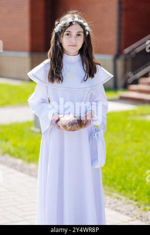 Lida, Biélorussie - 15 juin 2021 : fille portant une robe blanche tenant du pain, première cérémonie de communion Banque D'Images