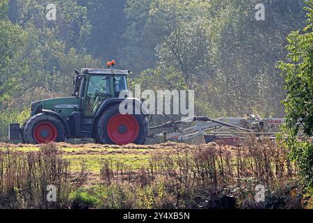 Landarbeit in Nordrhein-Westfalen Ein Schlepper des Herstellers Fendt befährt mit einem Heuwender eine Auenlandschaft um eine gleichmäßige Trocknung von dem Heu zu erzielen. Essen Rhénanie-du-Nord-Westphalie Deutschland *** travaux agricoles en Rhénanie-du-Nord-Westphalie Un tracteur du fabricant Fendt conduit une faneuse à travers un paysage de prairie pour obtenir un séchage uniforme du foin Essen Rhénanie-du-Nord-Westphalie Allemagne Banque D'Images