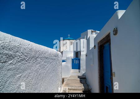 Murs blanchis à la chaux, marches, église orthodoxe à dôme bleu, croix blanche. Une image typique de la rue dans Santorini.Greece. traditio Banque D'Images