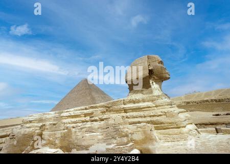 Le profil complet du Grand Sphinx avec la pyramide en arrière-plan à Gizeh. Banque D'Images