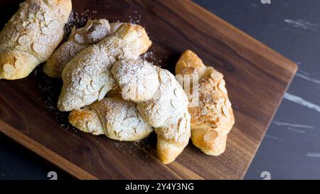 Croissants aux amandes saupoudrés de sucre en poudre et saupoudrés de flocons d'amandes. Parfait pour les blogs alimentaires, les livres de cuisine et le marketing de boulangerie pour les sites Web et l'impression Banque D'Images