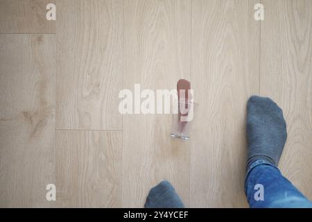 Accidentellement renversé du lait au chocolat sur tout le plancher en bois tout en portant des chaussettes à la maison Banque D'Images
