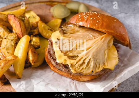 Hamburger avec des huîtres et du fromage cheddar sur une planche à découper en bois Banque D'Images