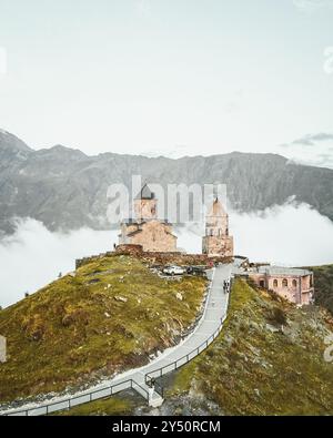Vue aérienne Gergeti trinity Church après le coucher du soleil, Géorgie. Stepanstminda célèbre monument touristique sur le sommet d'une colline avec les montagnes brumeuses du caucase arrière Banque D'Images