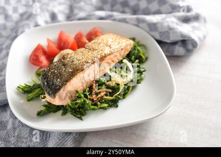 Filet de saumon rôti avec la peau sur un lit de légumes d'épinards et de tomates, repas sain pour perdre du poids avec un régime faible en glucides, espace de copie, focu sélectionné Banque D'Images