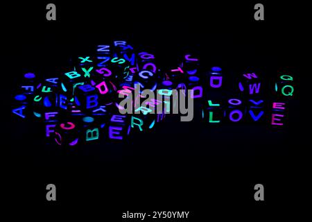 Les lettres de couleur néon sont dispersées sur un fond sombre avec un accent sur le mot LOVE affiché en évidence au centre Banque D'Images