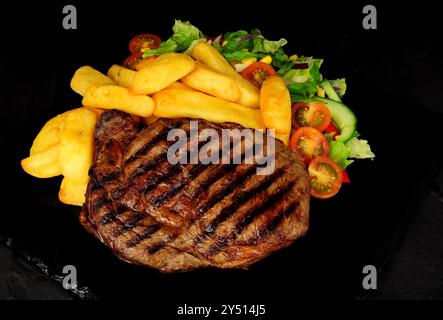 Steak de bœuf grillé avec grosses frites et salade Banque D'Images
