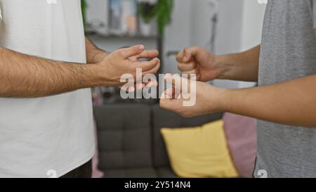 Deux hommes s'engageant dans un jeu amical de pierre-papier-ciseaux à l'intérieur, avec un accent sur les mains et les gestes. Banque D'Images