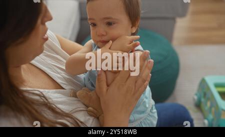 Femme tenant bébé dans le salon, exprimant l'amour et le lien entre la mère et le nourrisson dans un cadre de maison confortable Banque D'Images