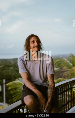 Homme en vacances sur l'île tropicale, assis sur la terrasse au coucher du soleil. Banque D'Images