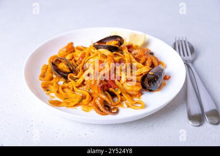 Pâtes Marinara aux crevettes, pieuvre et moules. Nouilles faites maison avec fruits de mer dans une sauce tomate. Plats italiens traditionnels. Mise au point sélective, gros plan. Banque D'Images