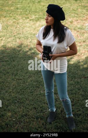 Photographe utilisant un appareil photo analogique dans un parc de la ville. Banque D'Images