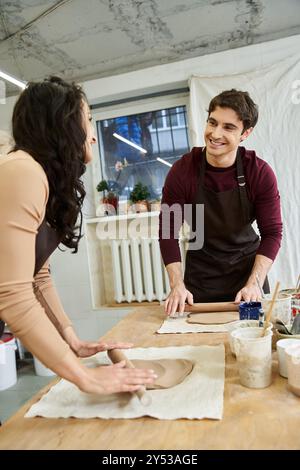 Un couple façonne joyeusement l'argile dans leur studio de poterie lumineux. Banque D'Images