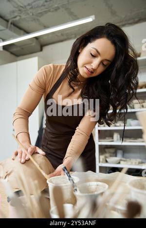 Femme positive faisant de la poterie dans un studio bien éclairé. Banque D'Images