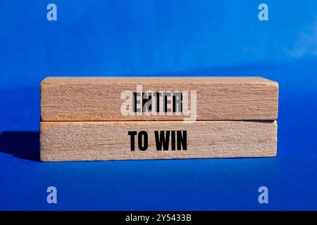 Participez pour gagner un message écrit sur des blocs de bois avec fond bleu. Entrez conceptuel pour gagner le symbole. Copier l'espace. Banque D'Images