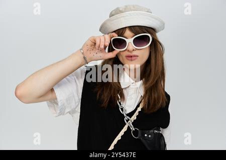 Un jeune homme respire la confiance dans les vêtements à la mode, posant de manière ludique sur un fond clair. Banque D'Images